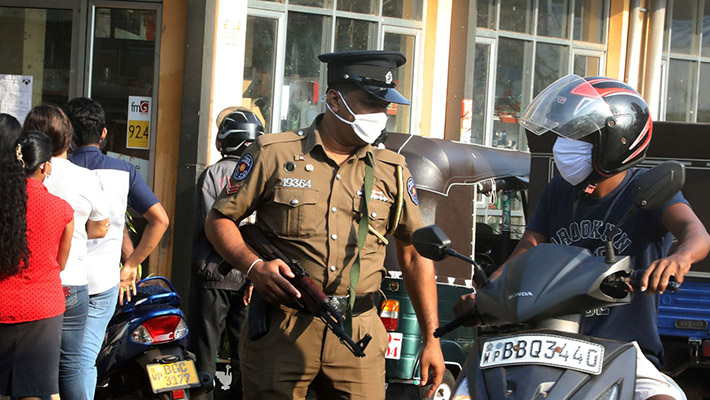 COLOMBO - SRI LANKA - MARCH 24: An armed Sri Lankan policeman talks to a scooter rider near a market in Colombo, Sri Lanka on March 24, 2020. With the risk of Coronavirus (Covid-19) spreading, the government declared an island-wide curfew since Friday to prevent the movement of people. With the curfew being relaxed at 6.00 am this morning, large crowds rushed to the markets to purchase their essentials. The curfew was re-imposed at 2.00 pm today and will be in force indefinitely in three districts identified as high-risk Covid-19 areas, namely the districts of Colombo, Gampaha and Kalutara. So far Sri Lanka has reported 101 Coronavirus positive cases. (Photo by Stringer/Anadolu Agency via Getty Images)